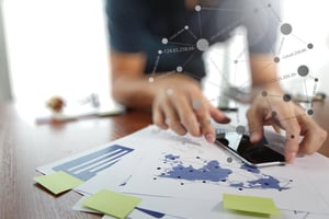 business documents on office table with smart phone and digital tablet and man working in the background